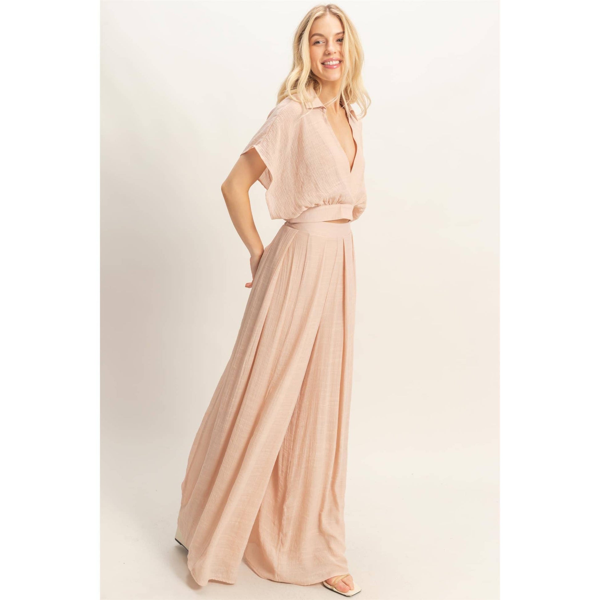 Woman wearing a long, light pink dress against a white background