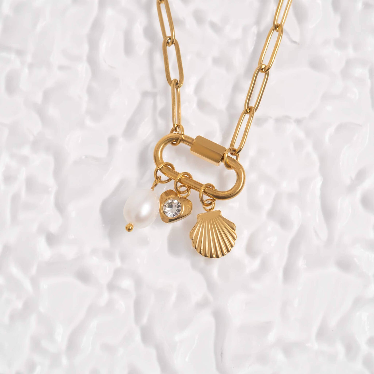 Gold necklace with charms on a textured white background