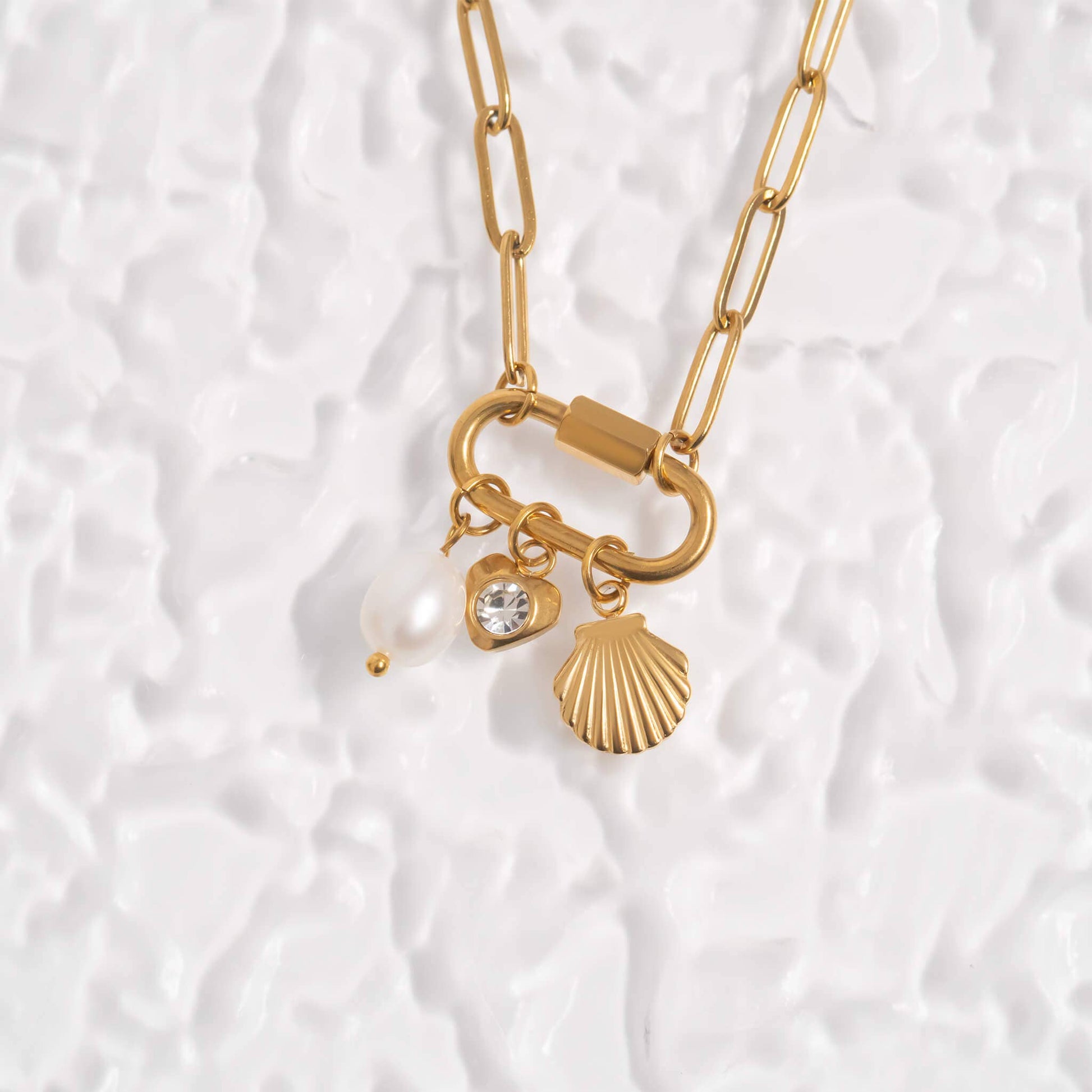 Gold necklace with charms on a textured white background