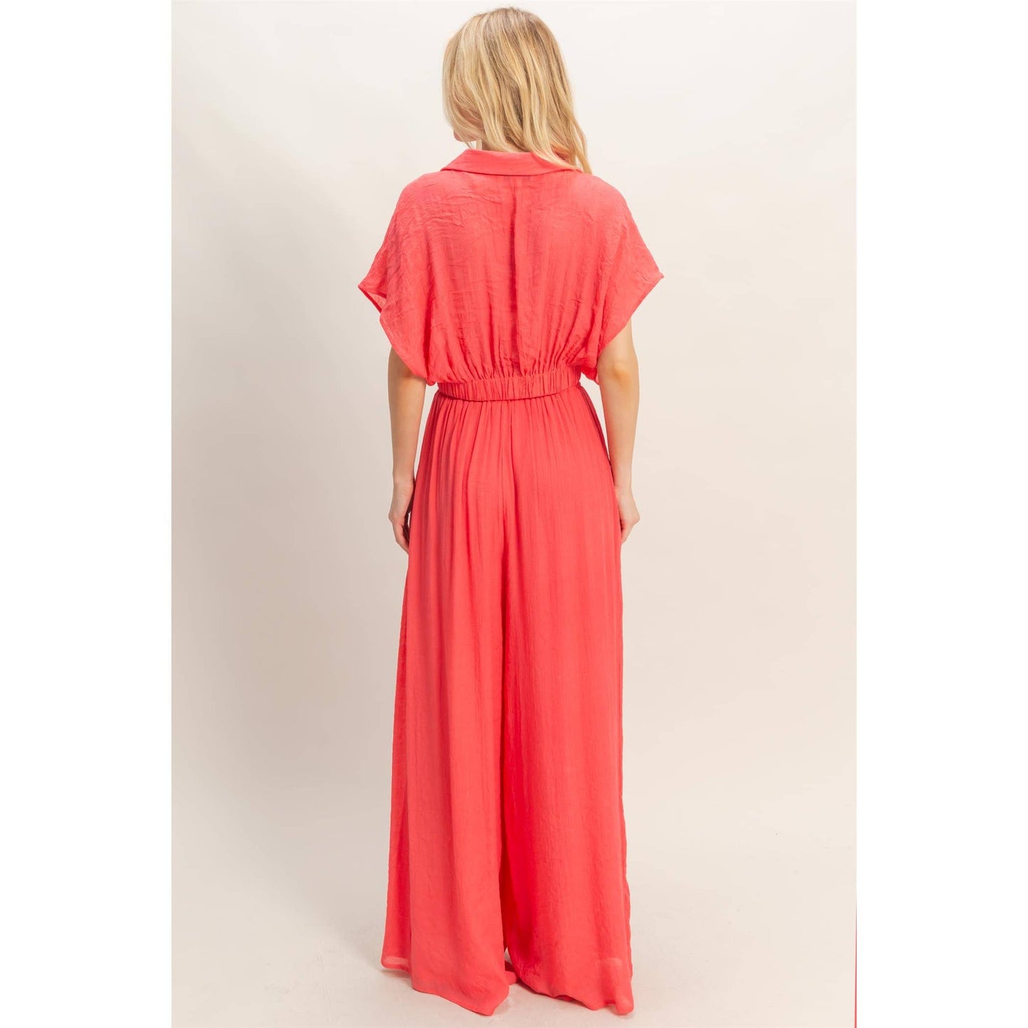 Woman wearing a coral dress against a plain background