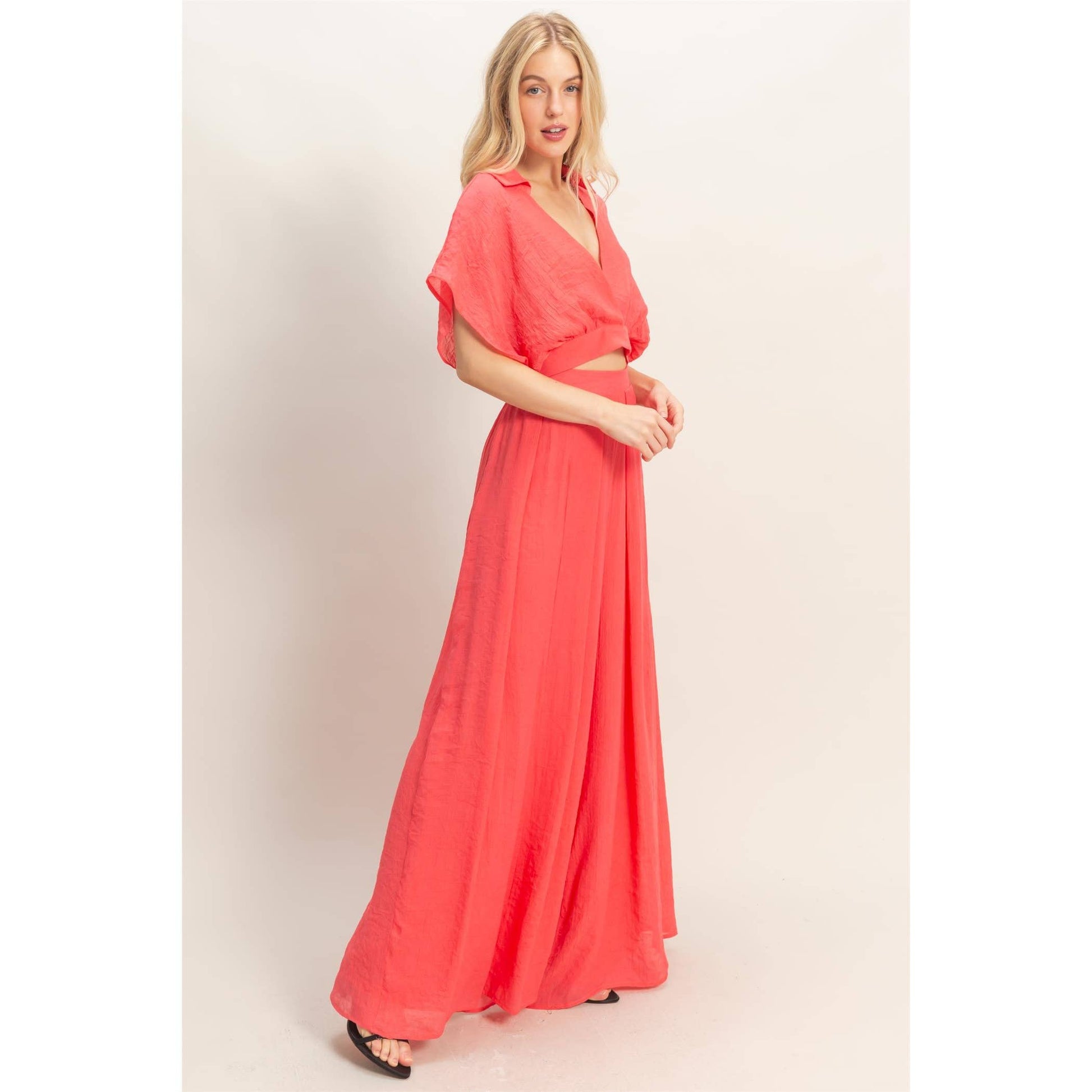 Woman wearing a coral dress against a plain background