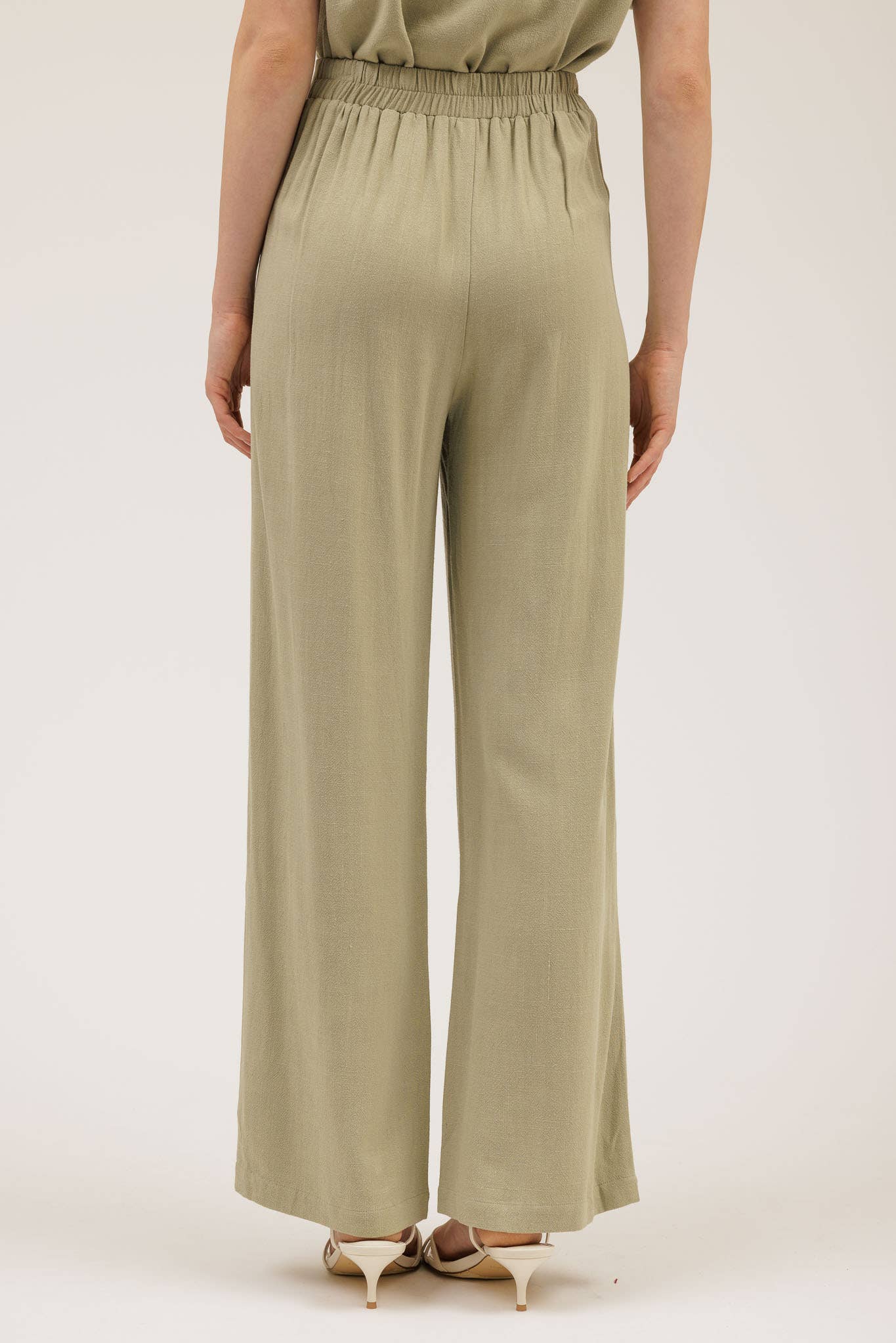 Person wearing a pair of green wide-leg pants on a white background