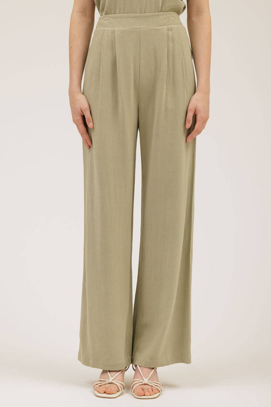 Person wearing a pair of light green wide-leg pants on a plain background