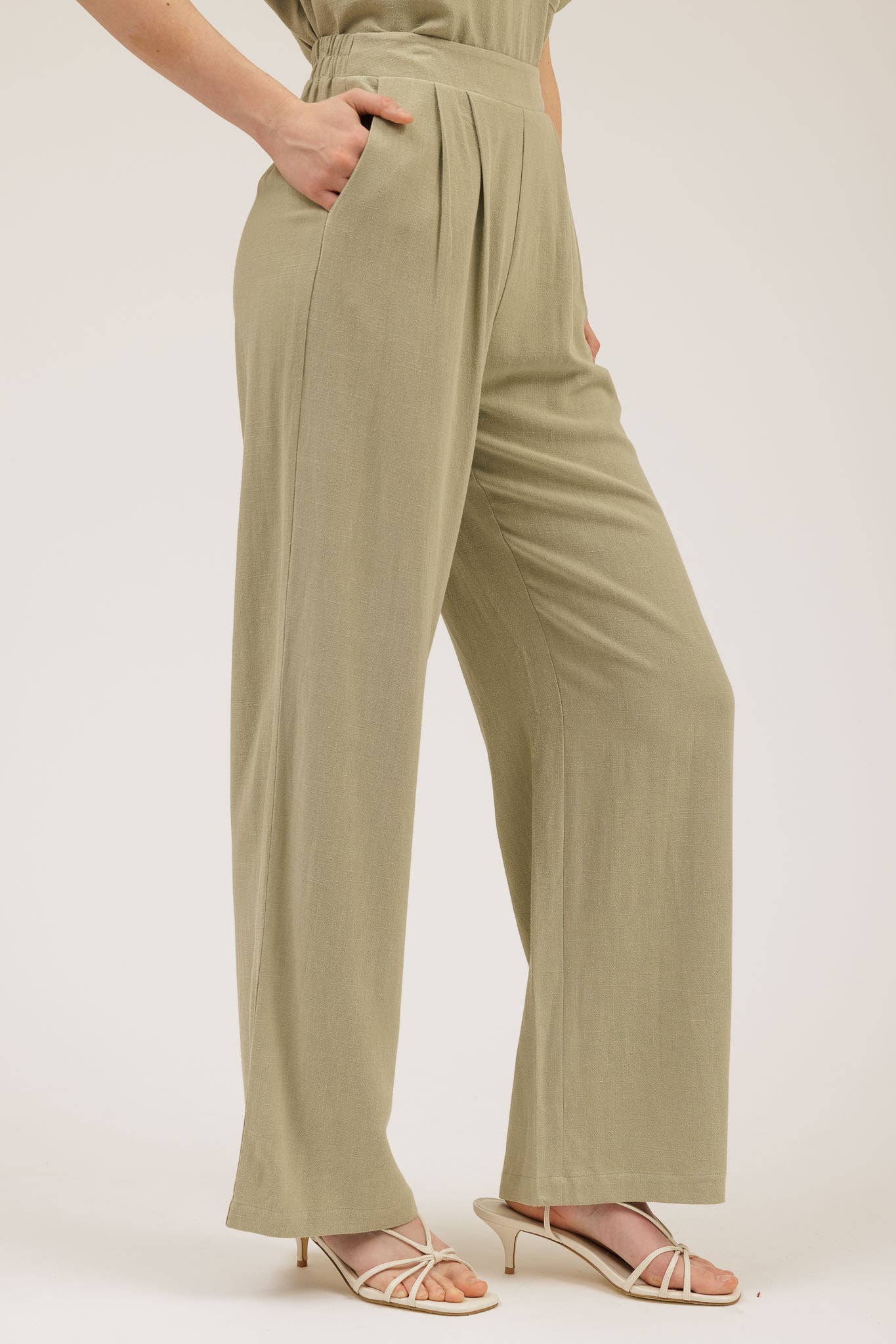 Person wearing a pair of olive green pants on a white background
