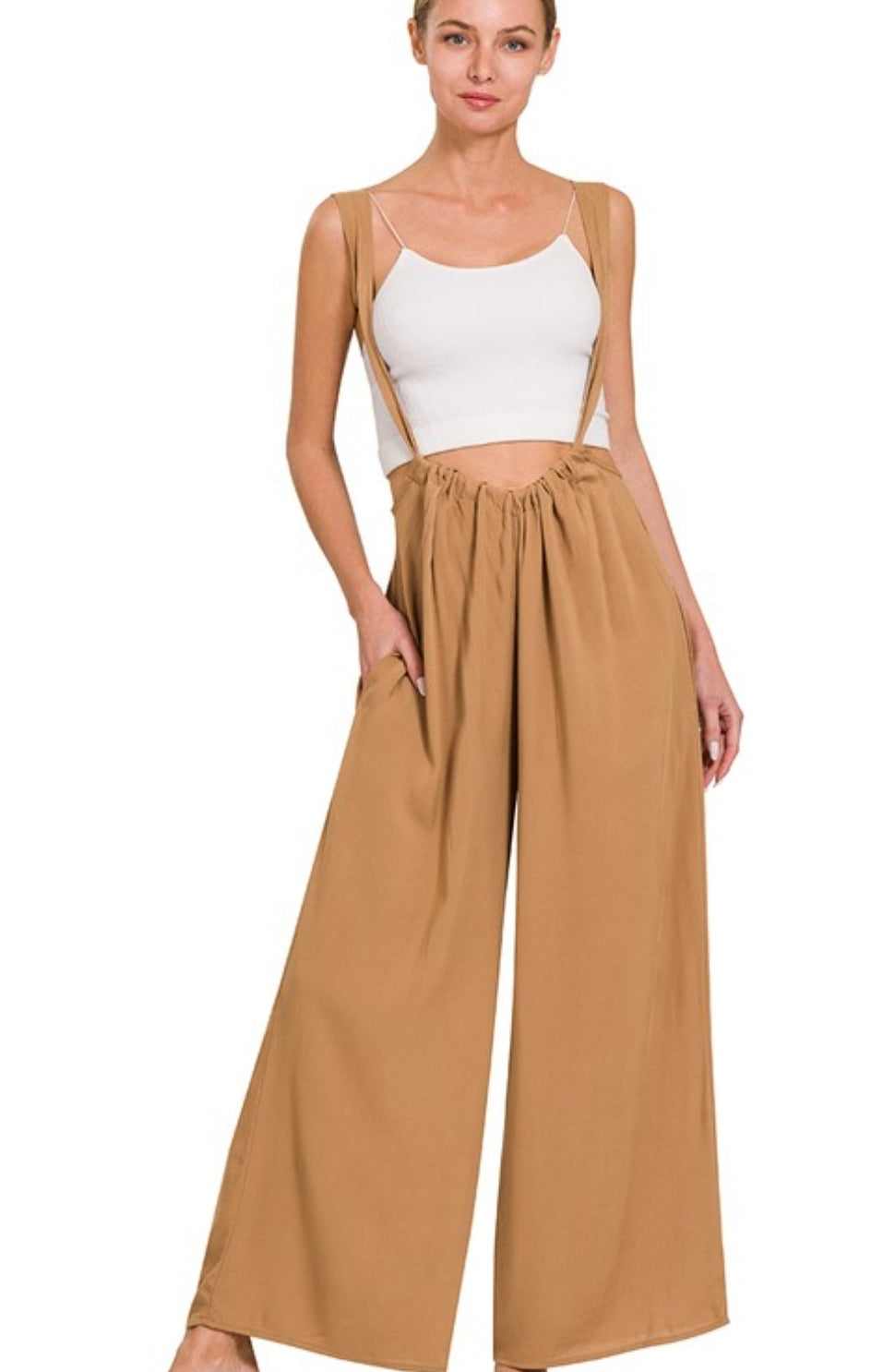 Woman wearing a white top and tan wide-leg pants on a white background