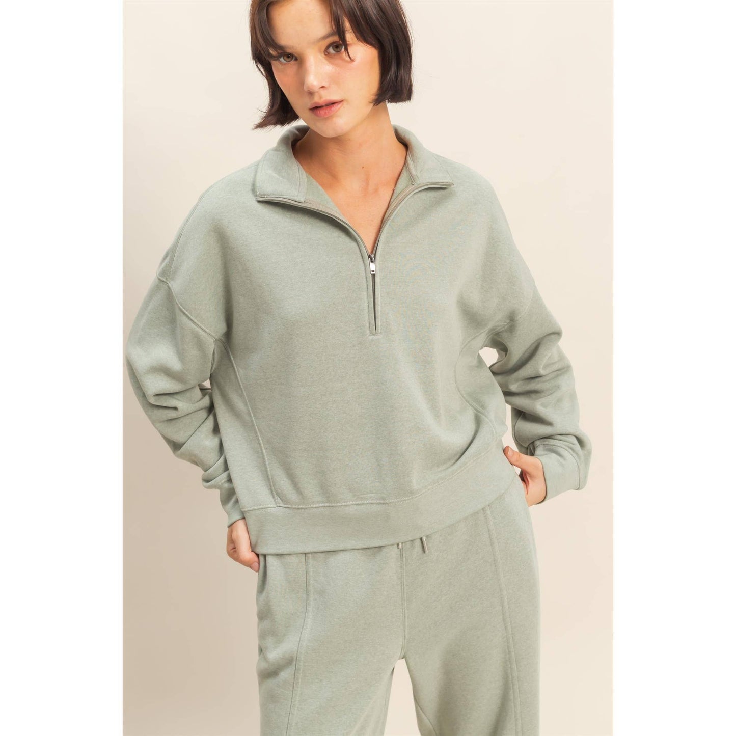 Woman wearing a light green tracksuit against a plain background