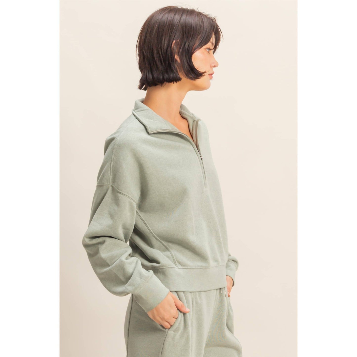 Person wearing a light green tracksuit against a plain background