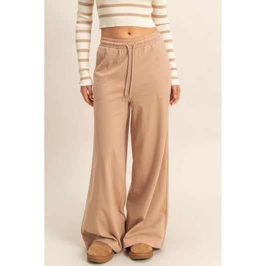 Person wearing beige wide-leg pants and a striped sweater on a plain background