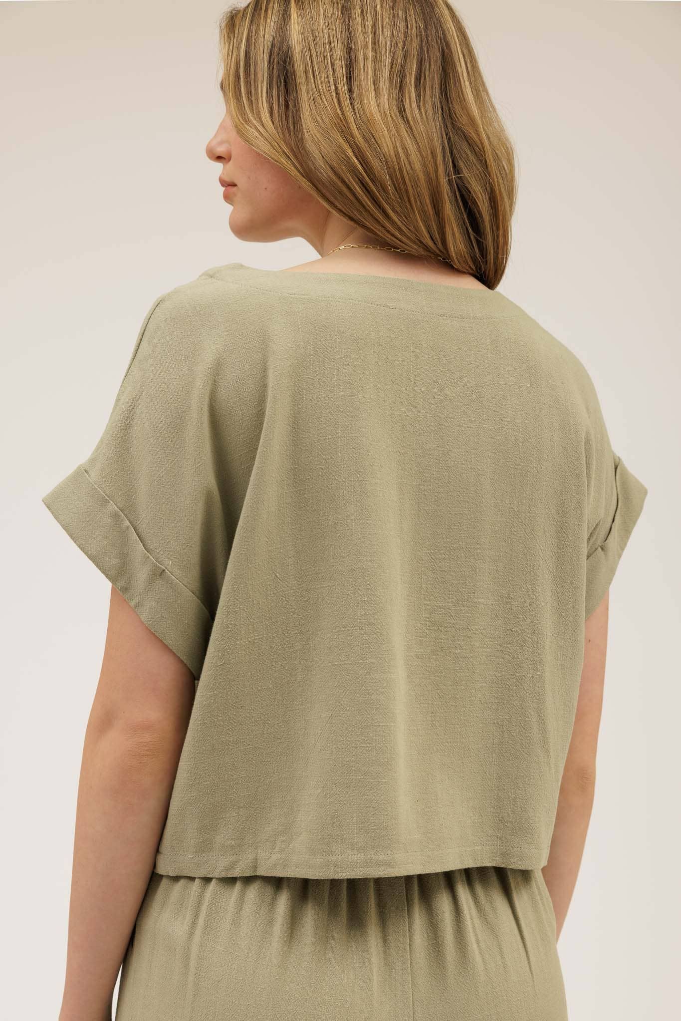 Woman wearing a green top and pants against a plain background