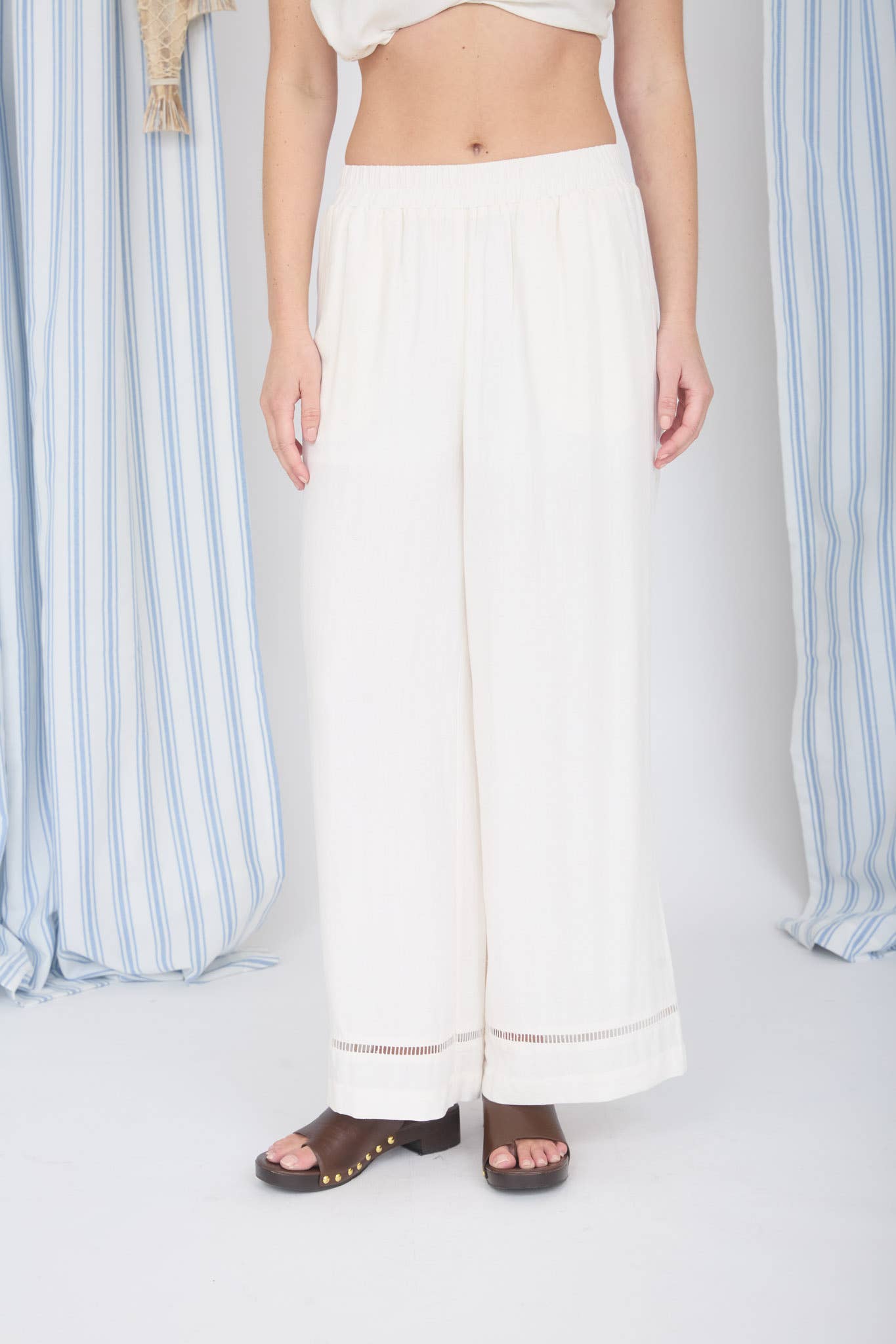 Person wearing white pants standing in front of a striped curtain