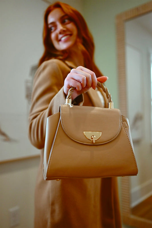 Woman holding a beige handbag indoors