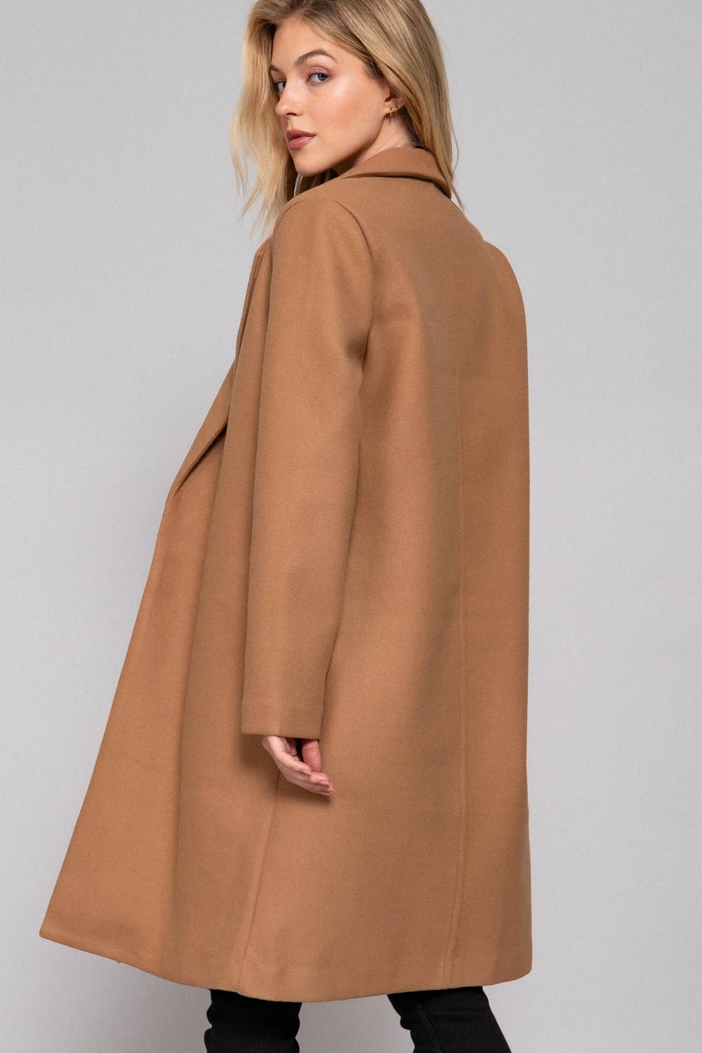 Woman wearing a brown coat against a plain background