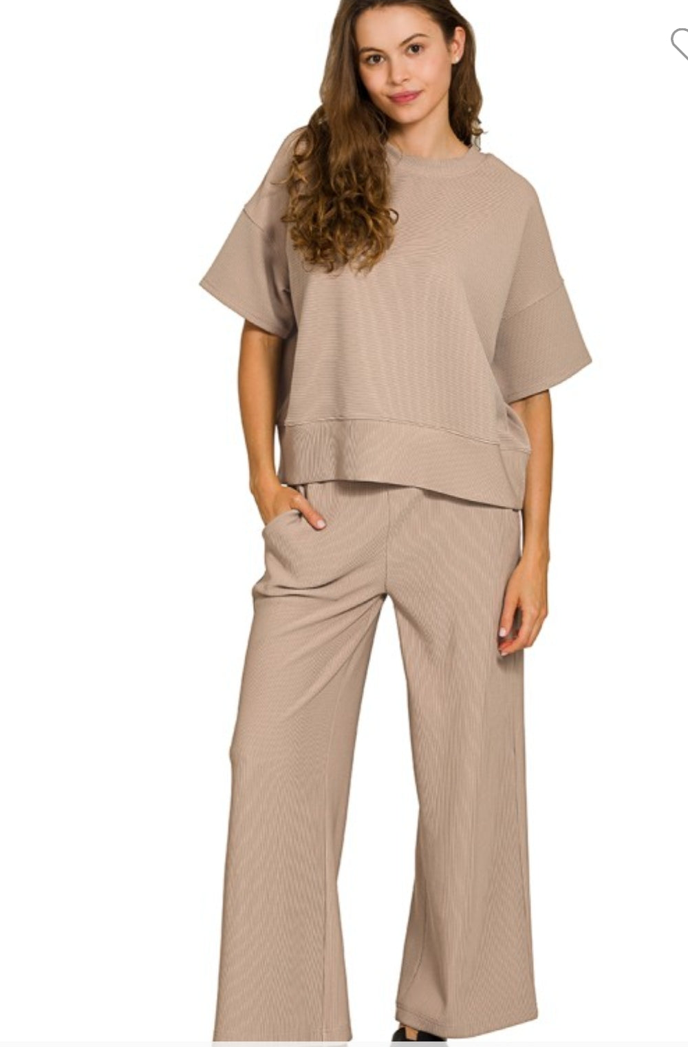 Woman wearing a beige outfit with a top and pants on a white background
