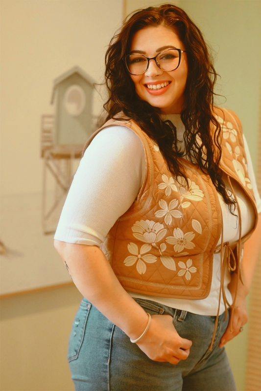Woman wearing a floral embroidered vest in an indoor setting